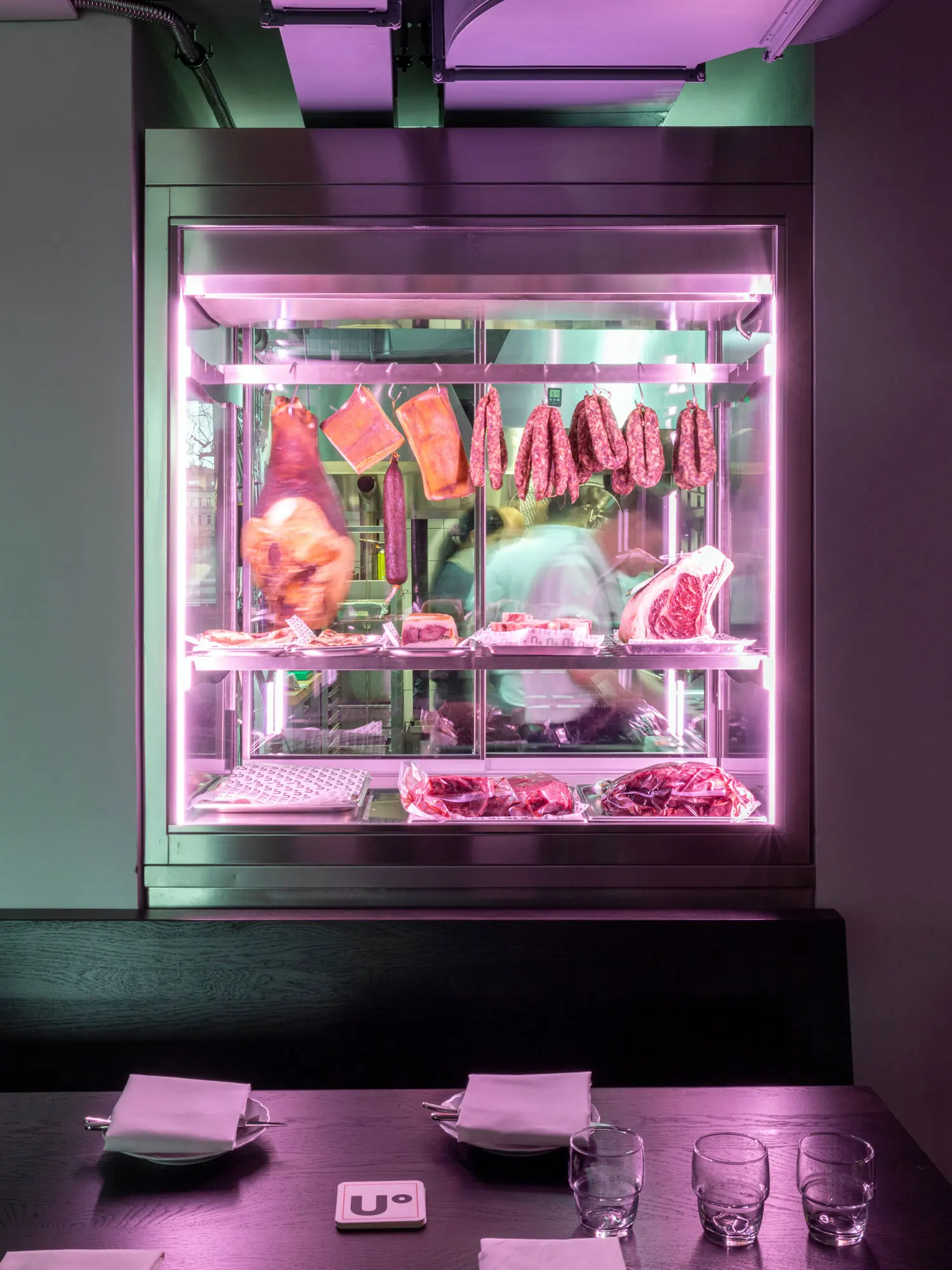 Meat display case with cured meats in a modern restaurant interior.